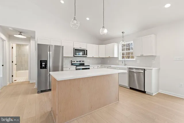 a large white kitchen with lots of counter space wooden floor and appliances