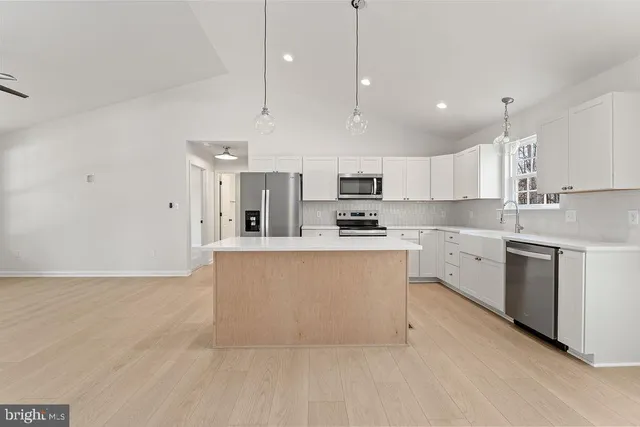a kitchen with kitchen island a sink stainless steel appliances and white cabinets