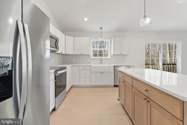 a kitchen with white cabinets and window