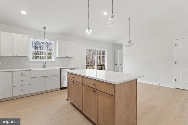 a kitchen with stainless steel appliances a dining table chairs refrigerator and sink
