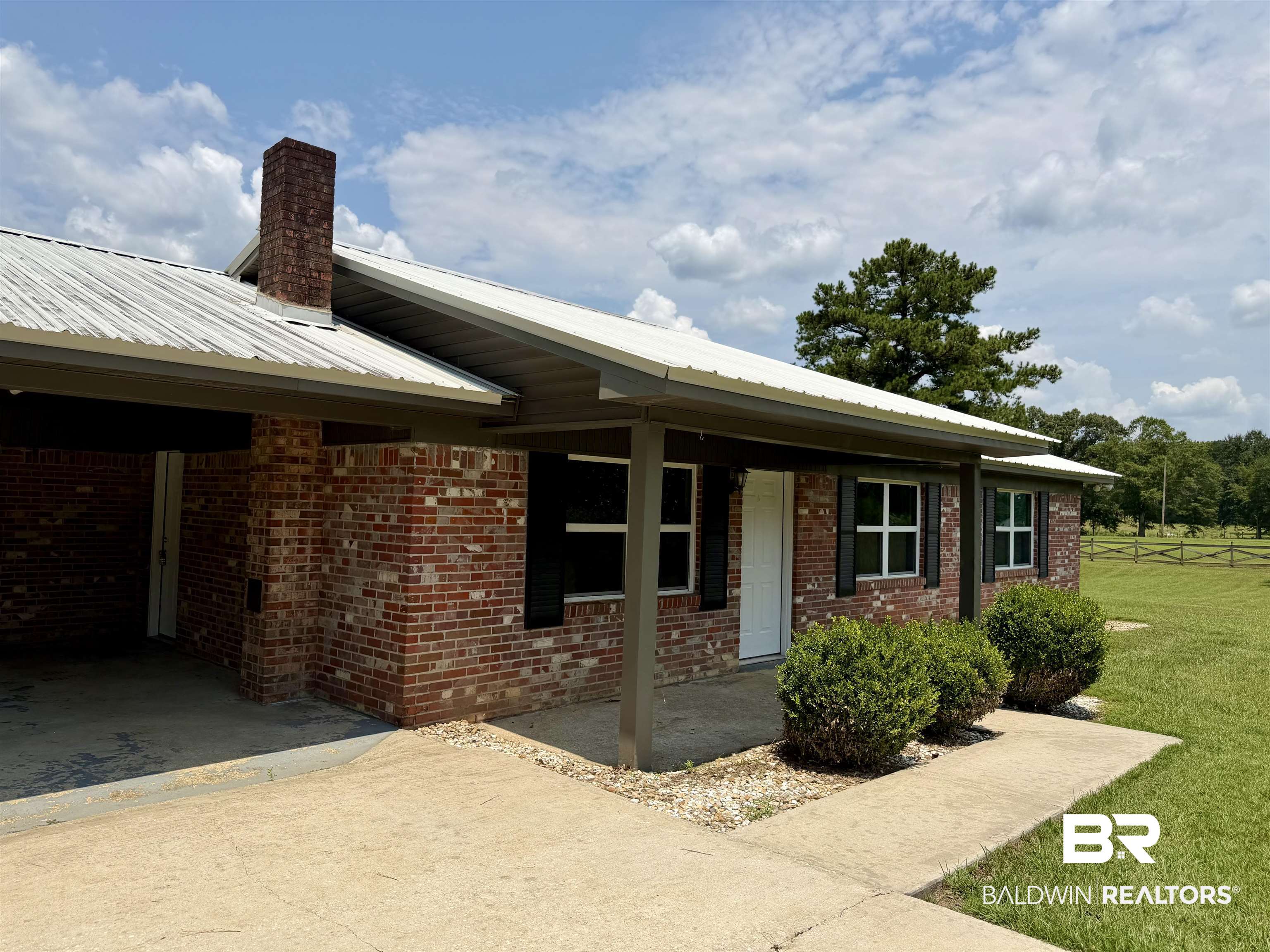11115 Appleton Road Castleberry, AL 36432 - Photo 2 of 18 Brick exterior featuring a white metal roof, covered front porch, and black window shutters