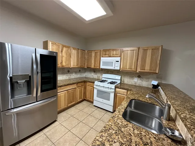 a kitchen with granite countertop a refrigerator stove and sink
