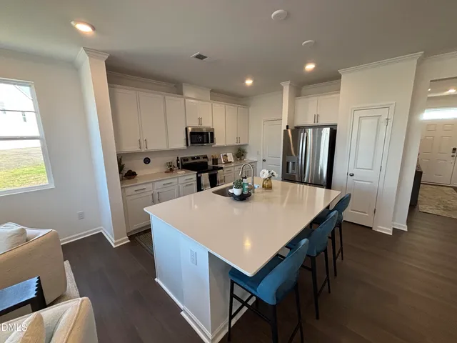 a kitchen with stainless steel appliances a kitchen island hardwood floor sink stove refrigerator and cabinets