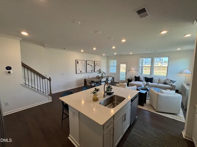 a living room with furniture kitchen view and a wooden floor