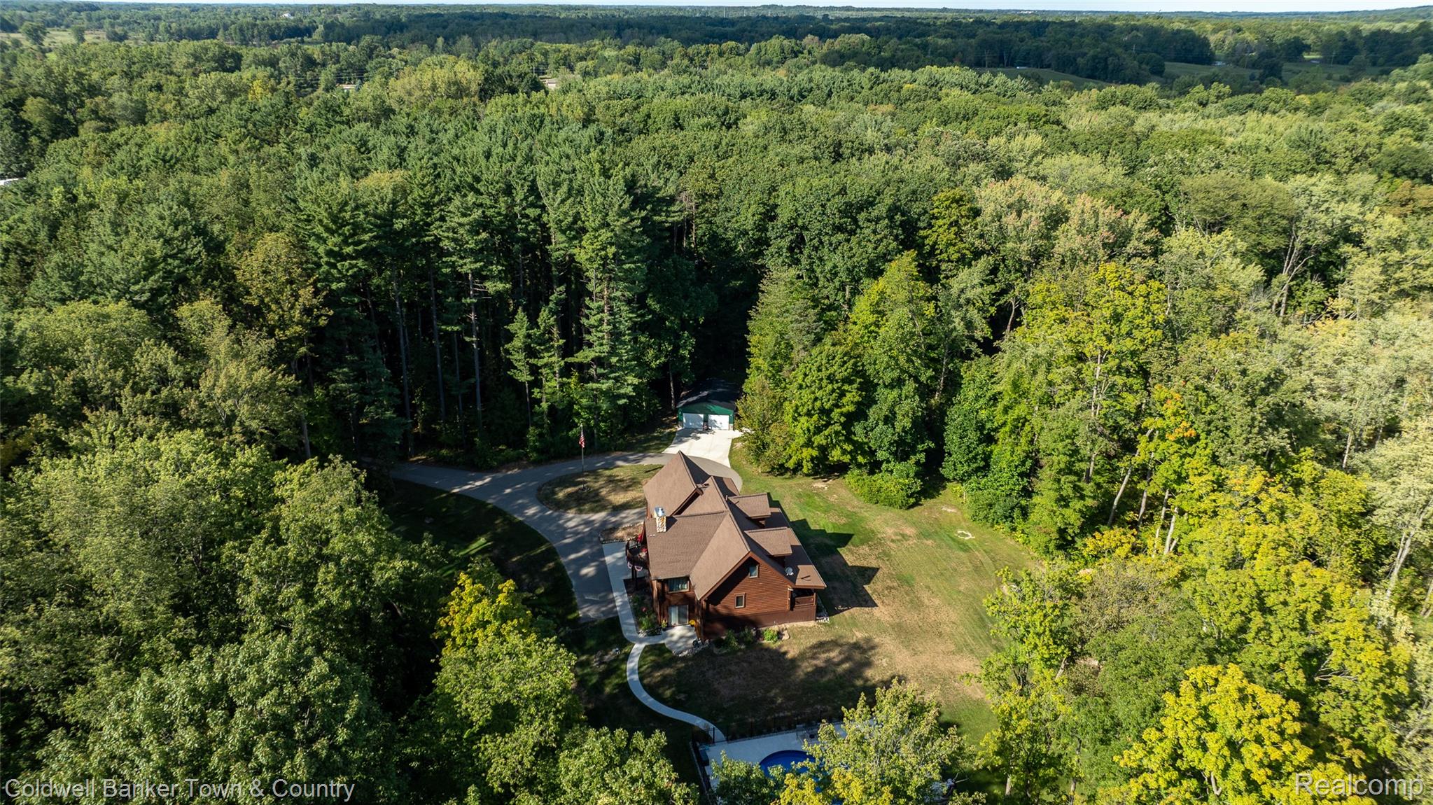 7023 Munsell Road Howell, MI 48843 - Photo 13 of 55 Wood-sided residence with multiple gables, surrounded by dense mature trees