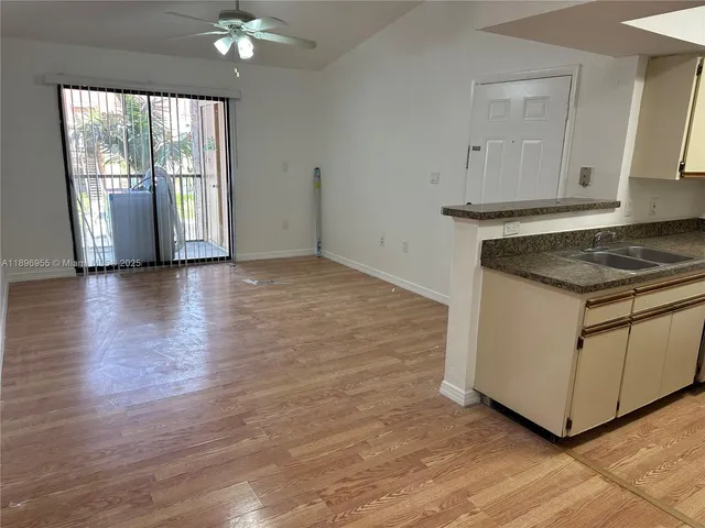 a kitchen with granite countertop a stove a sink and white cabinets with wooden floor next to windows