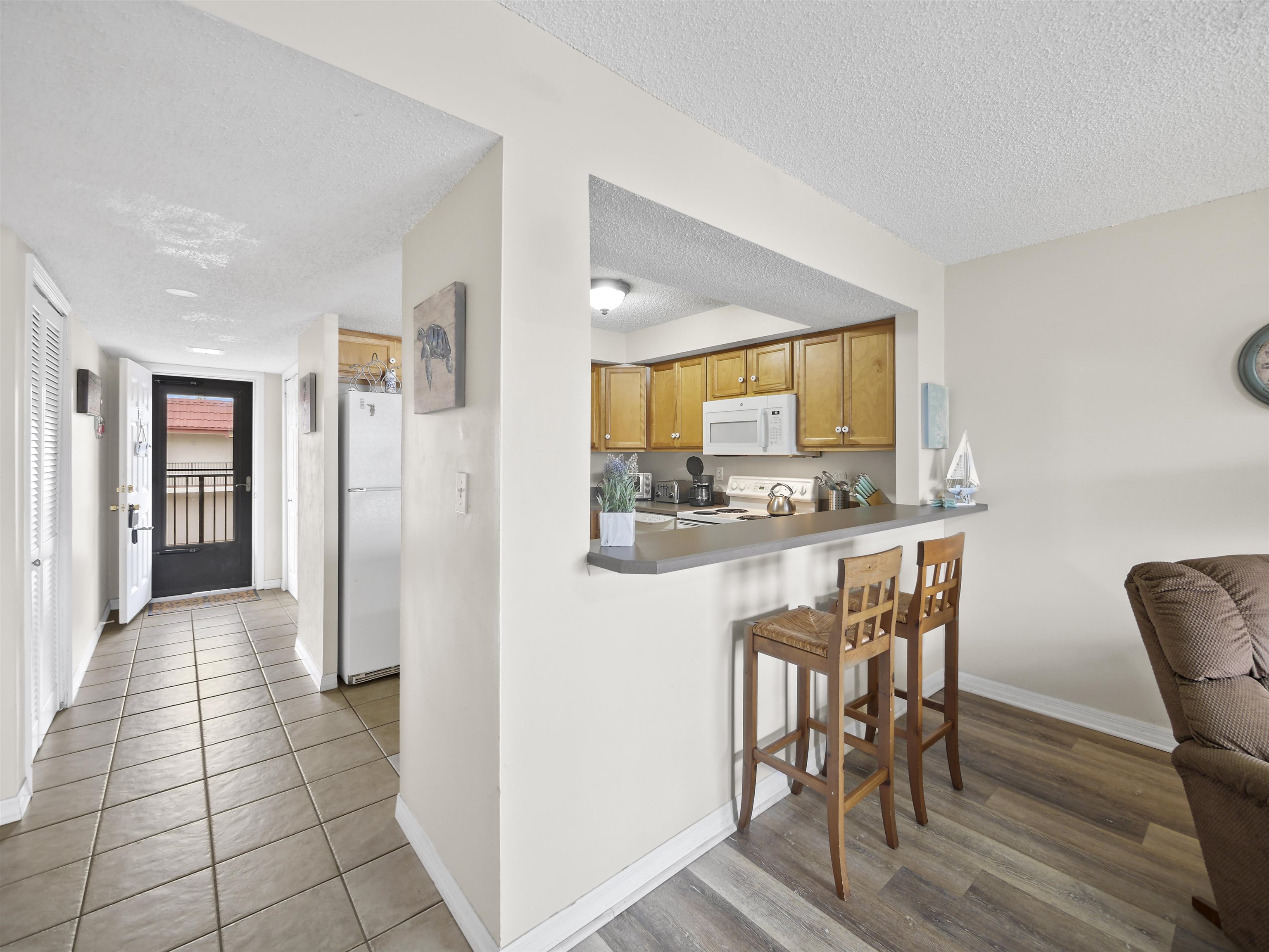 7175 A1A South St. Augustine, FL 32080 - Photo 11 of 35 a kitchen with granite countertop a refrigerator and wooden cabinets