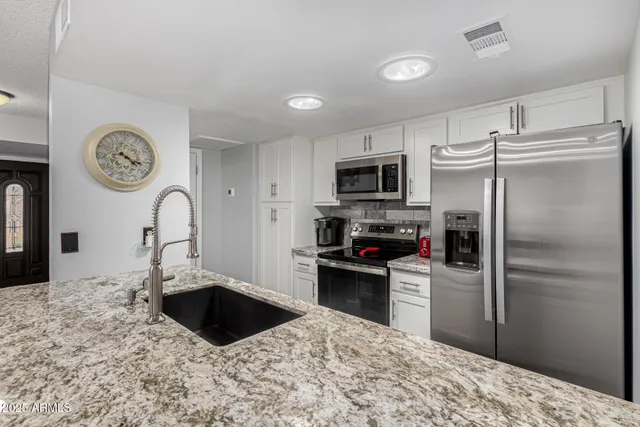 a kitchen with a refrigerator sink and cabinets