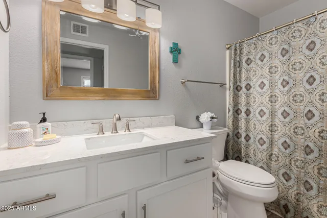 a bathroom with a granite countertop toilet sink and mirror
