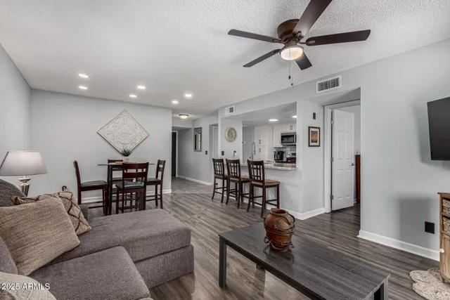 a living room with furniture kitchen view and a wooden floor