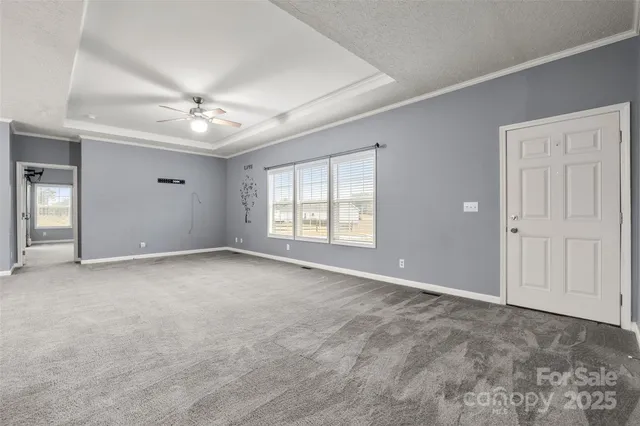 a view of an empty room with window and kitchen view