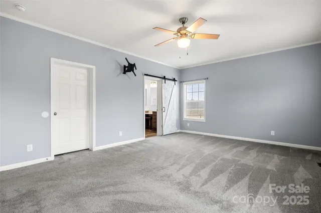 an empty room with windows and chandelier fan