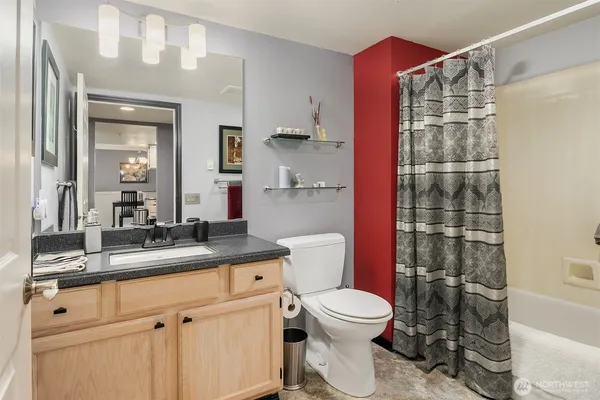 a bathroom with a granite countertop sink a toilet a mirror and shower
