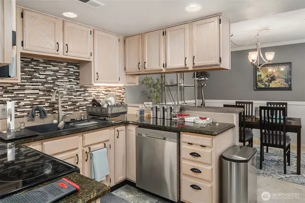 a kitchen with granite countertop a sink a stove and cabinets