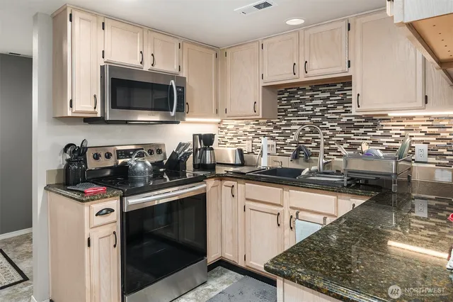 a kitchen with stainless steel appliances granite countertop a sink a stove a microwave and cabinets