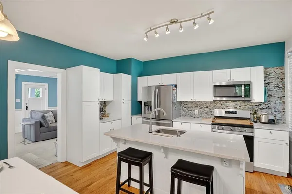 a kitchen with stainless steel appliances a sink a stove a refrigerator cabinets and a dining table