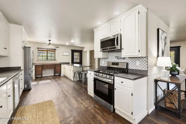 a kitchen with stainless steel appliances granite countertop a stove top oven a sink dishwasher and a refrigerator with wooden floor