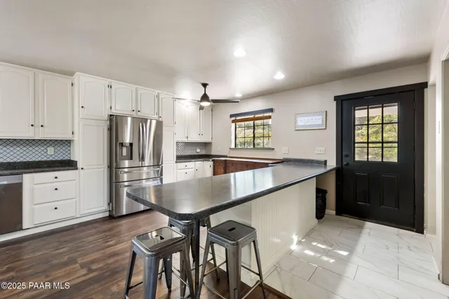 a kitchen with granite countertop a refrigerator a stove cabinets and wooden floor