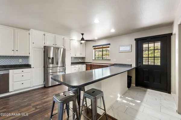 a kitchen with granite countertop a refrigerator a stove cabinets and wooden floor