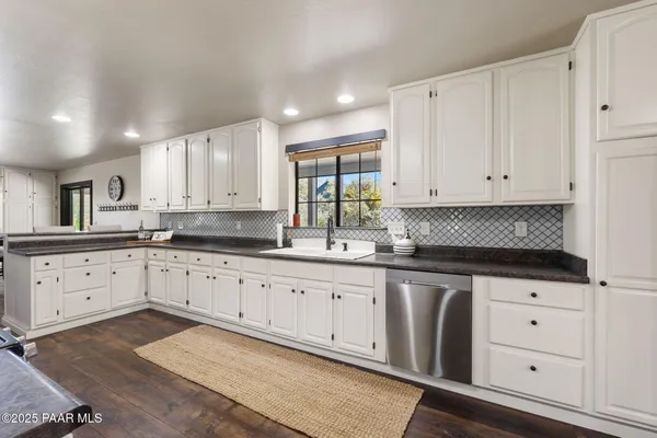 a kitchen with granite countertop white cabinets white stainless steel appliances with a sink and dishwasher