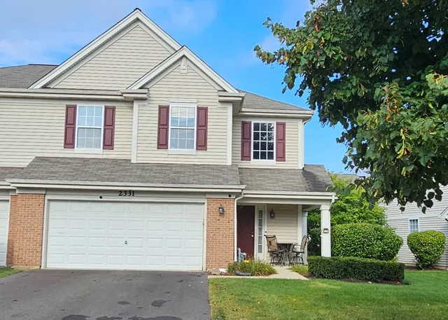 a view of a white house with a small yard plants and a large tree
