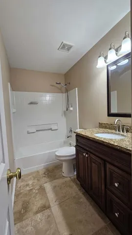 a bathroom with a granite countertop sink toilet mirror and bathtub