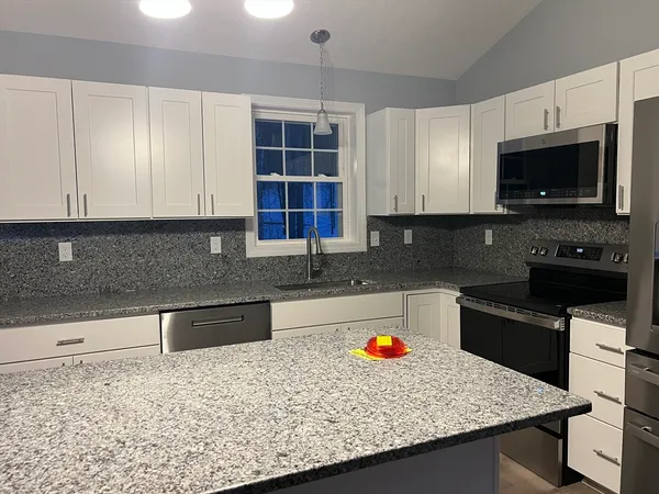 a kitchen with granite countertop a sink a stove and a microwave