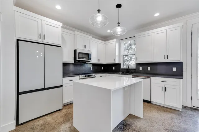 a kitchen with kitchen island a white cabinets and refrigerator