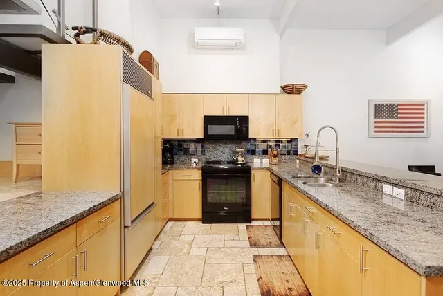 a kitchen with granite countertop a sink a stove top oven and stainless steel appliances