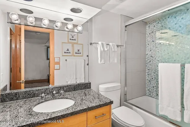 a bathroom with a granite countertop sink toilet a mirror a shower and a sink
