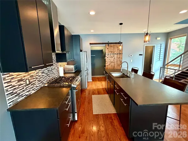 a kitchen with stainless steel appliances granite countertop a sink a stove and a refrigerator