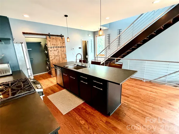 a kitchen with stainless steel appliances granite countertop a sink a stove and a wooden floor