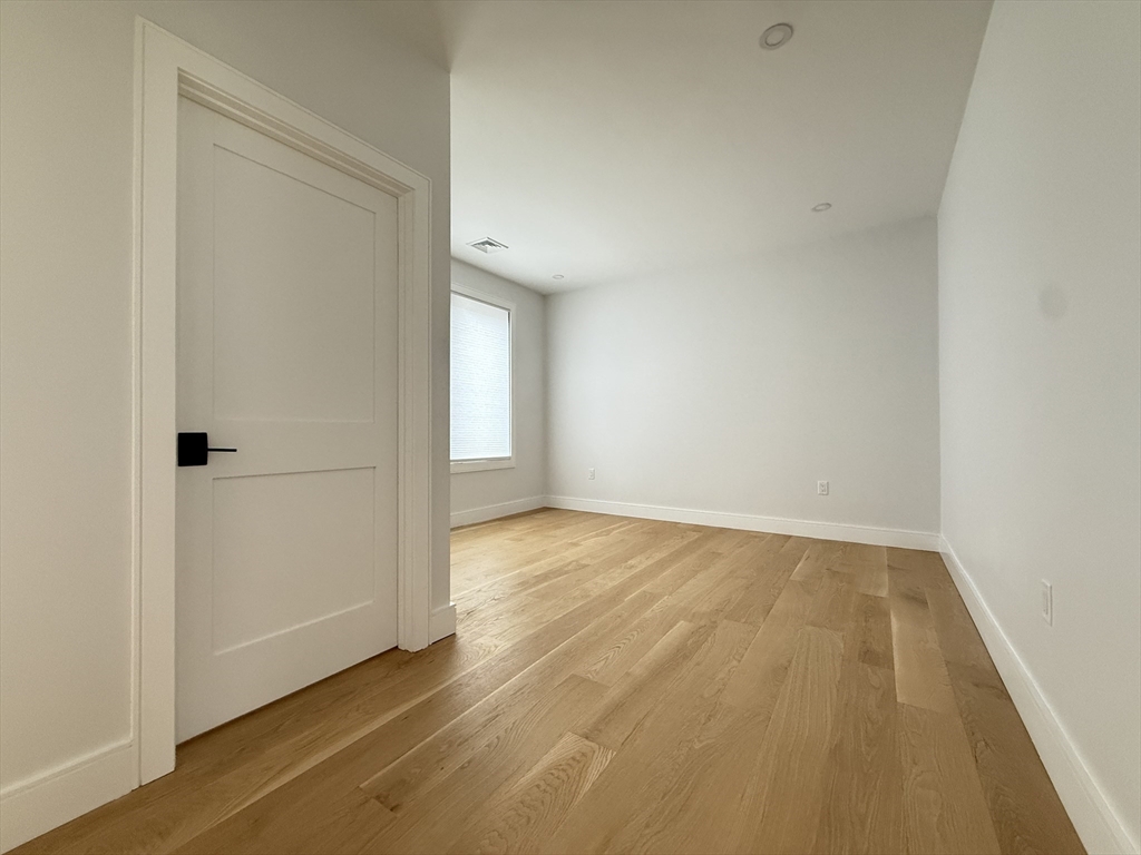 809-811 Heath Street, Unit 811 Brookline, MA 02467 - Photo 19 of 35 an empty room with wooden floor and windows