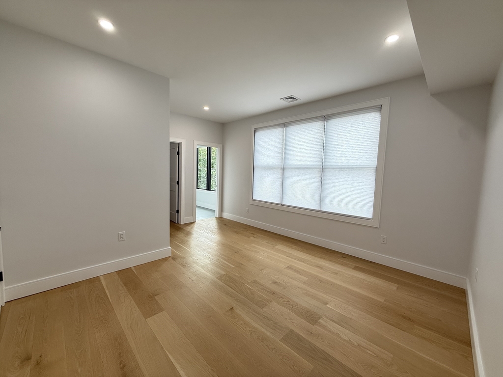 809-811 Heath Street, Unit 811 Brookline, MA 02467 - Photo 25 of 35 an empty room with wooden floor and windows