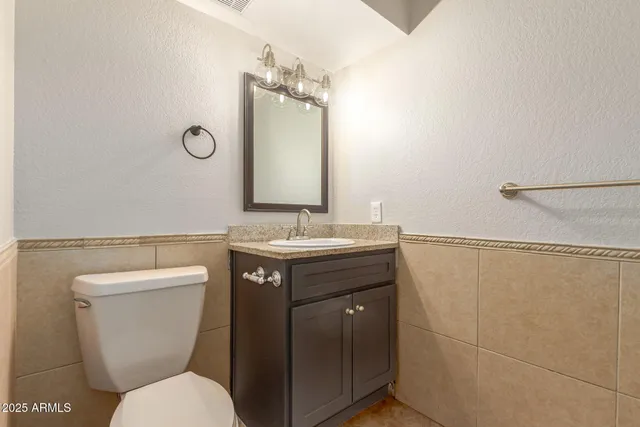 a bathroom with a toilet sink vanity and mirror