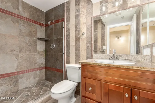 a bathroom with a granite countertop sink toilet a mirror and shower