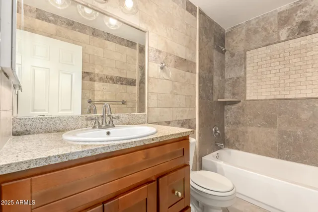 a bathroom with a granite countertop sink toilet mirror and bathtub