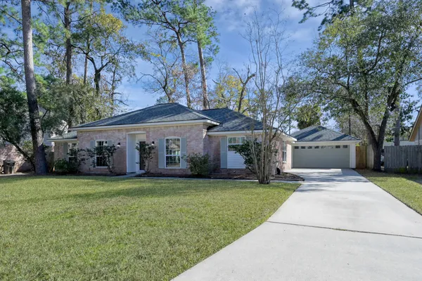 a front view of a house with a garden and trees