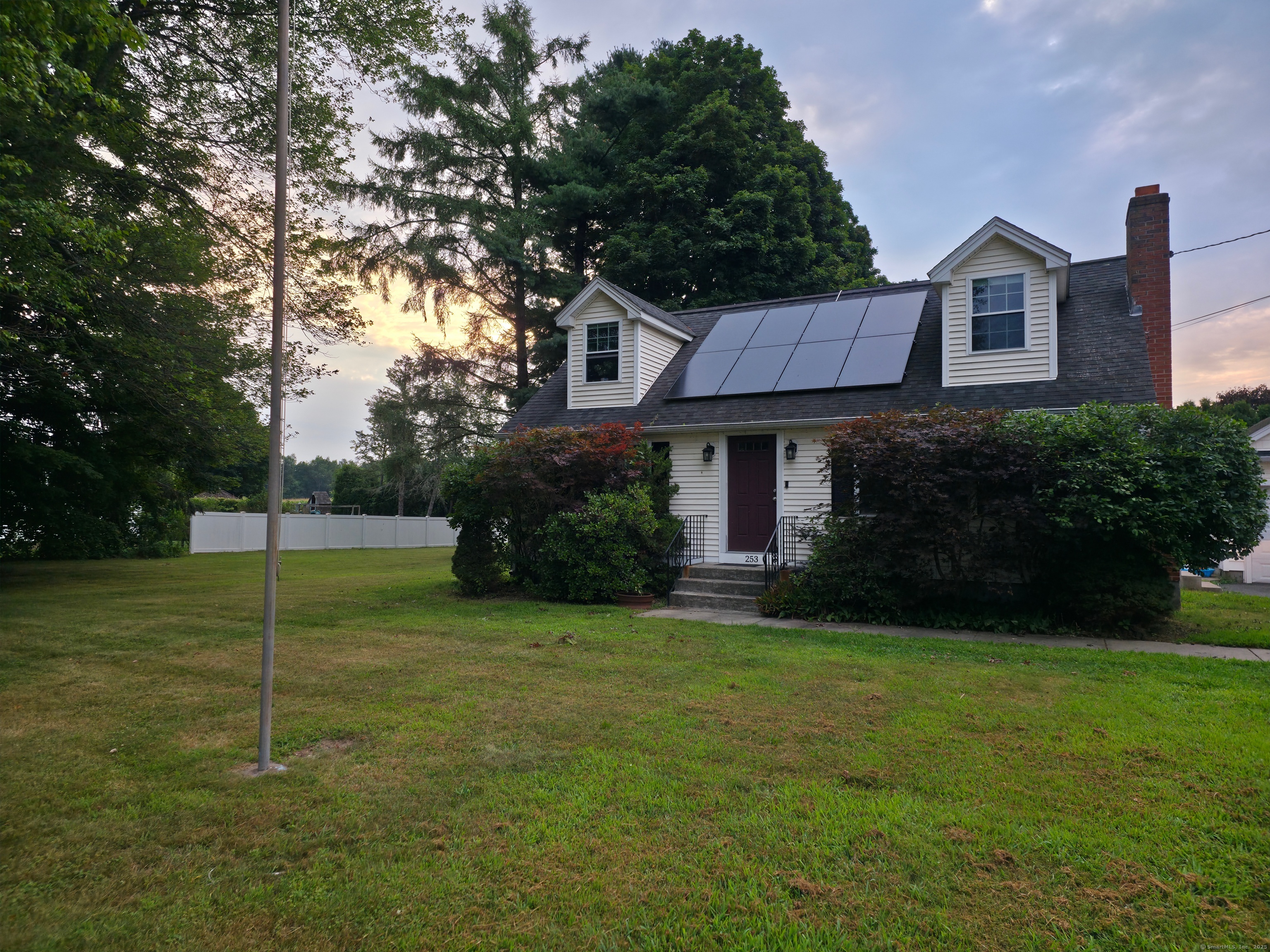 a view of a house next to a big yard and large trees