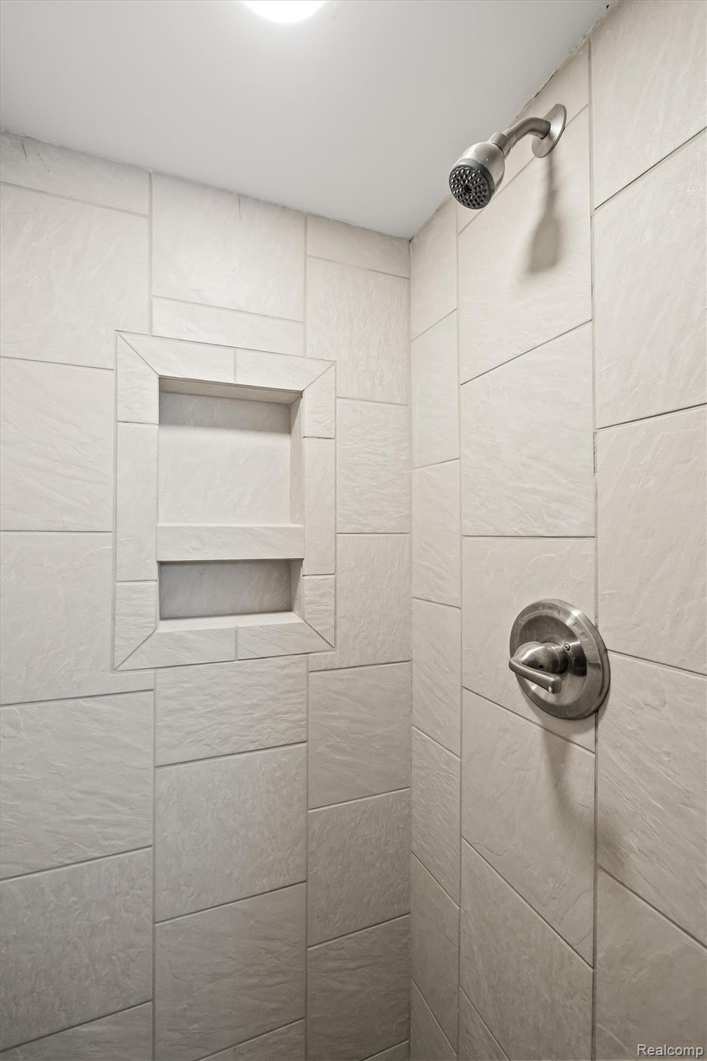 347 Highland Avenue Rochester, MI 48307 - Photo 49 of 59 Shower stall with light-toned rectangular tile surround, recessed storage niche, and brushed nickel fixtures