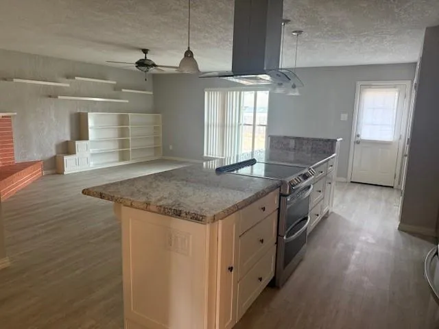 a kitchen with stainless steel appliances granite countertop a sink a stove and a wooden floors