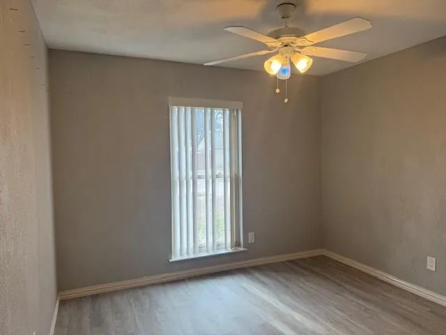 an empty room with windows and fan