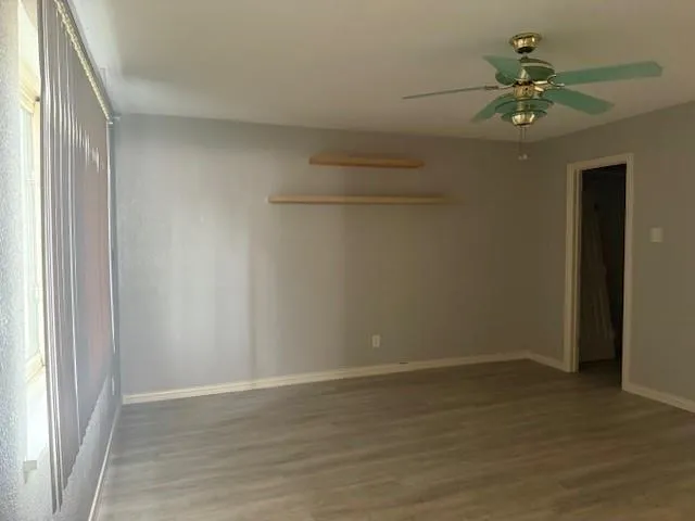 a view of a room with a chandelier fan and wooden floor