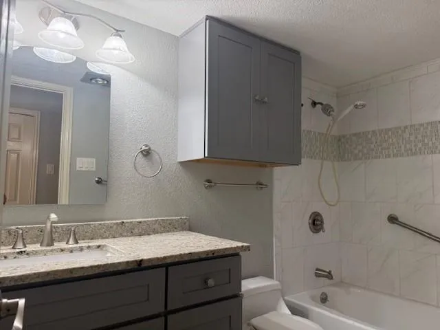a bathroom with a granite countertop sink a toilet and shower