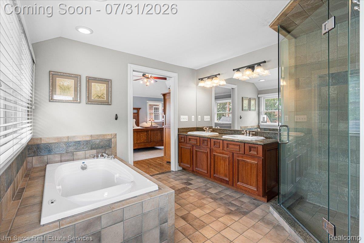 637 Washington Road Grosse Pointe, MI 48230 - Photo 25 of 40 Bathroom featuring a built-in soaking tub with tile surround, a glass-enclosed shower, and a double vanity with wood cabinetry and undermount sinks