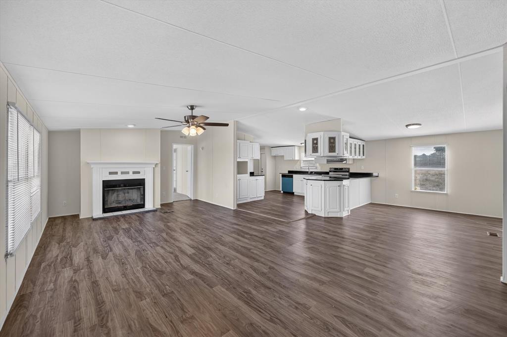 246 PR-4443 Rhome, TX 76078 - Photo 5 of 35 Open-concept living area with wood-finish flooring, a white mantel fireplace, and a ceiling fan