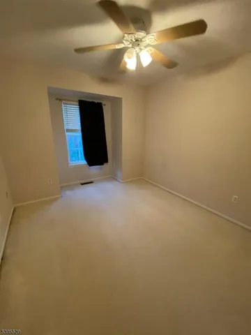 an empty room with a ceiling fan and a window