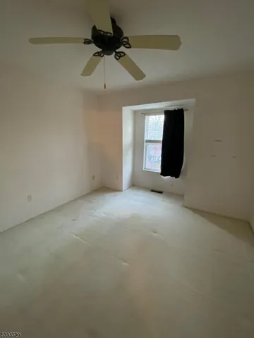 an empty room with ceiling fan and window