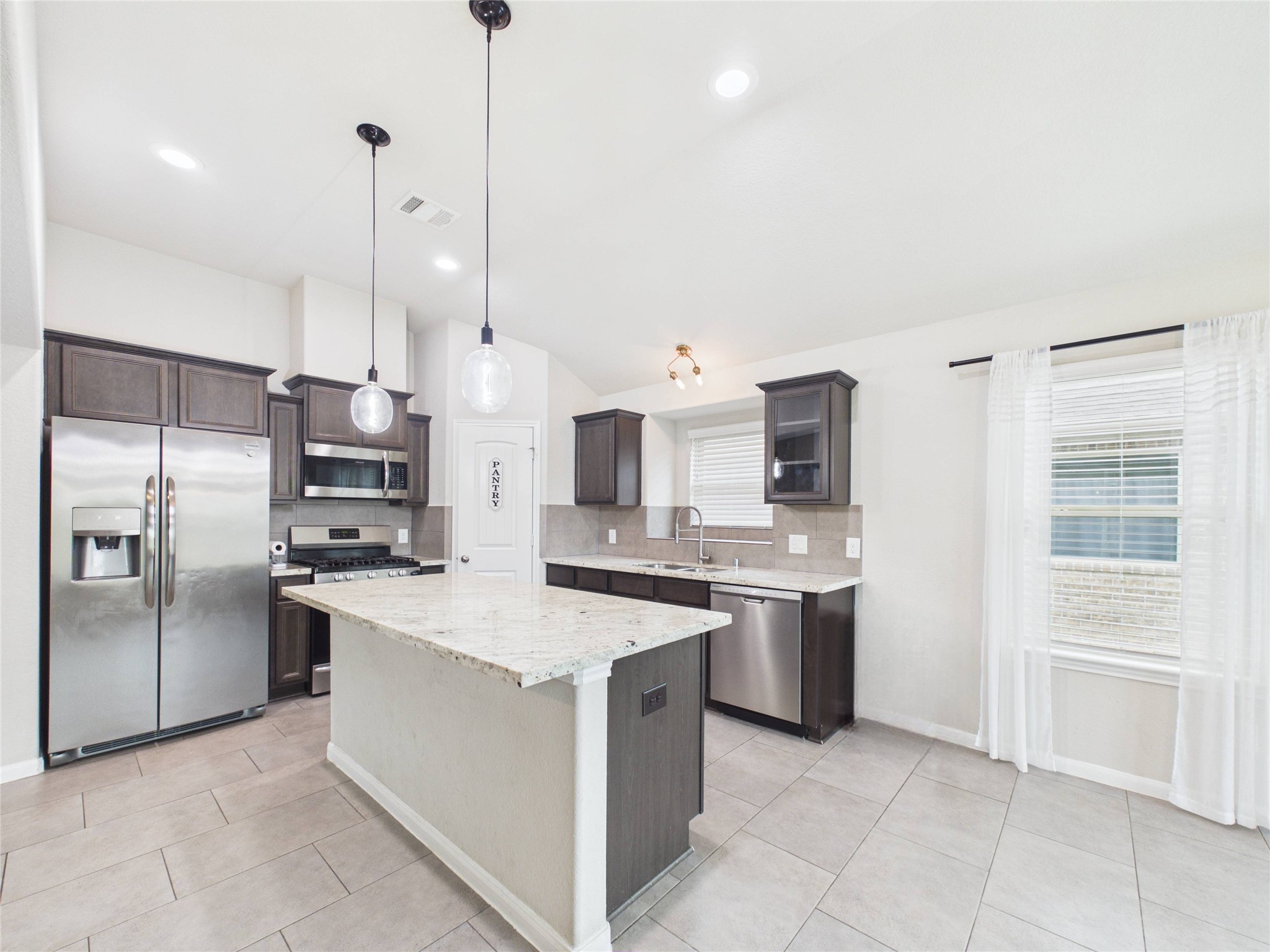 721 Rim Water Drive Alvin, TX 77511 - Photo 12 of 40 a kitchen with stainless steel appliances a stove a sink and a refrigerator