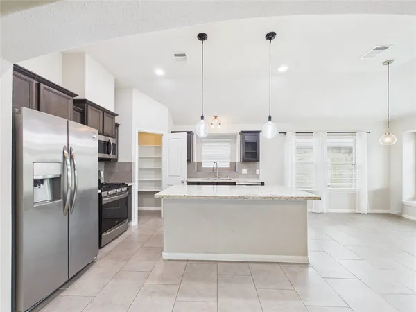 a kitchen with stainless steel appliances granite countertop a refrigerator a oven and a sink
